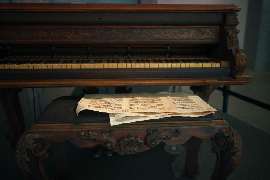 Elegant vintage piano with ornate carvings and classic sheet music on bench.